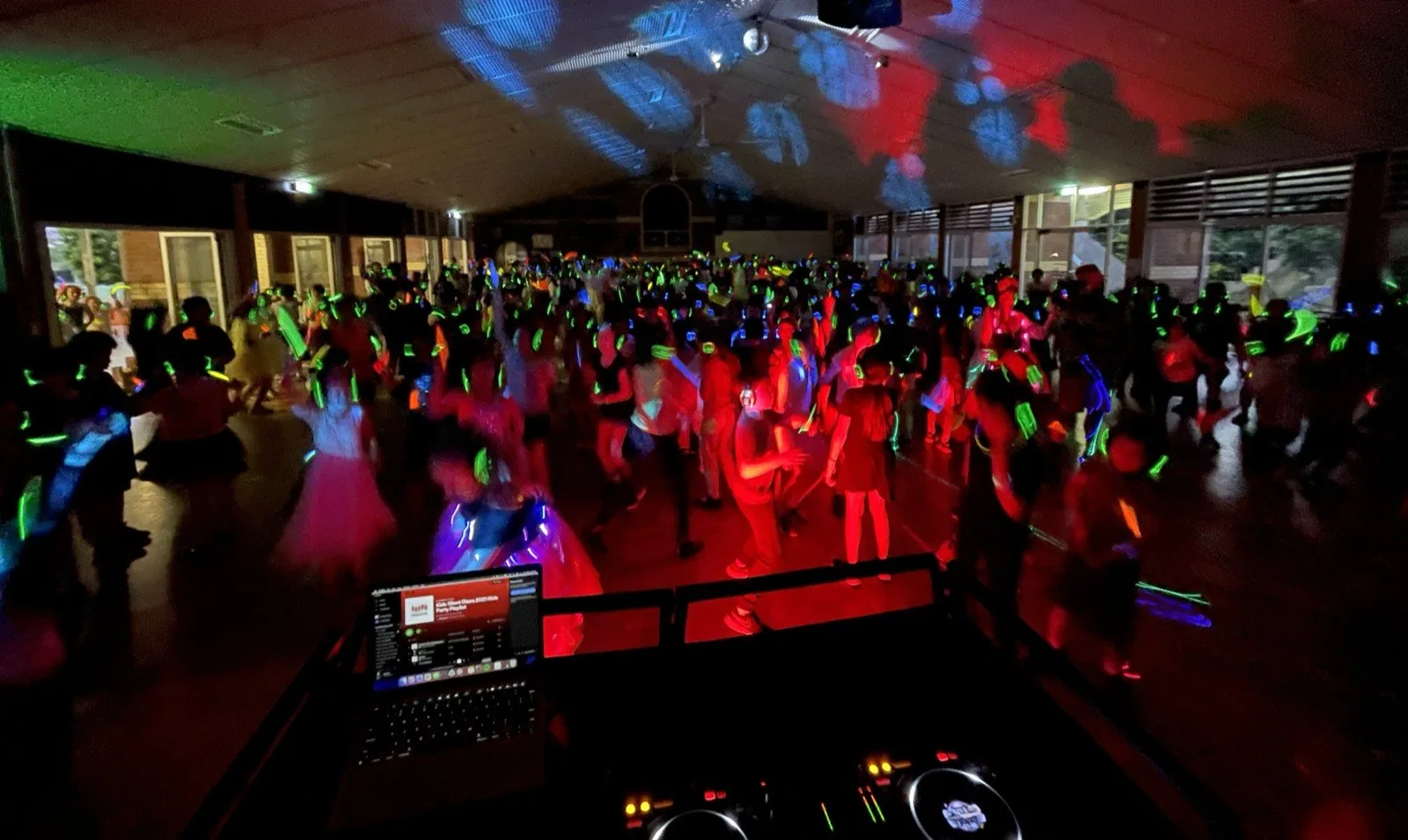 School silent disco event with children dancing under glow lights